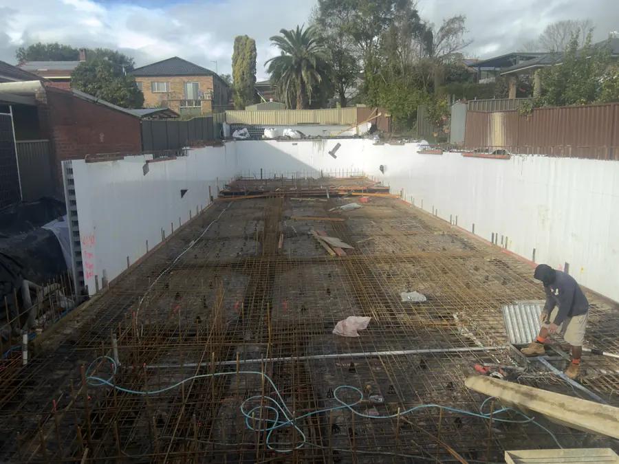 After: the same site with walls formed and steel reinforcement laid across the floor