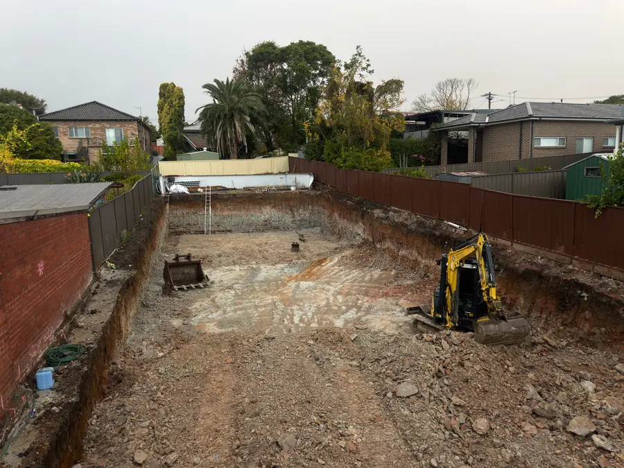 Before: Insight mini excavator in the finished dig, cut down into rock between back fences